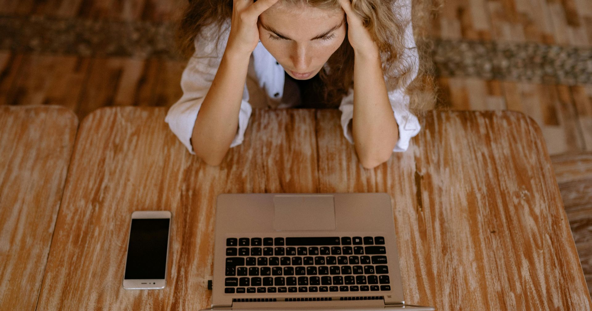 High Angle Photo of Woman Looking Upset in Front of Silver Laptop