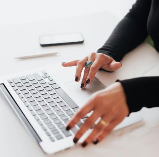 Crop female using touchpad on laptop in office